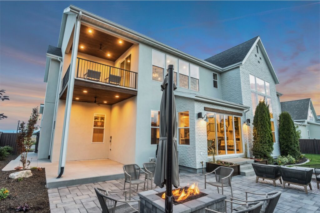 A house with a balcony and an outdoor fire pit at dusk.